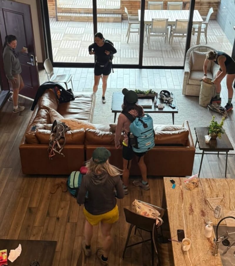 group of women gearing up with hiking backpacks in a lodge living room before a Zion National Park hike