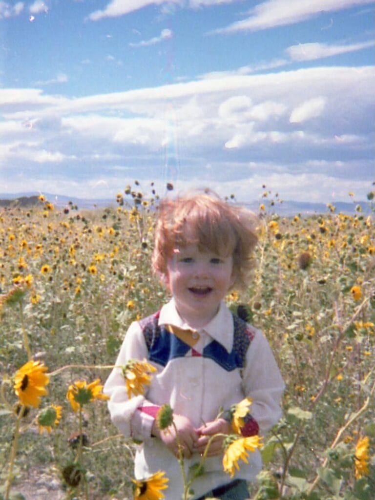Young Paul Ferney smiling in a sunflower field, vintage film photo